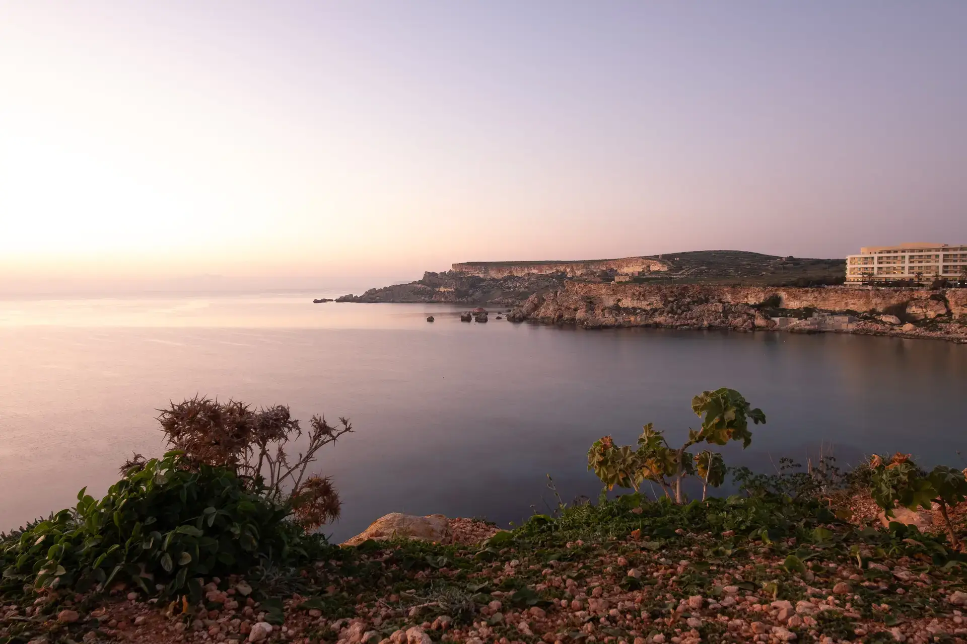 Golden Bay, Malta at sunset with warm golden light reflecting on the water.